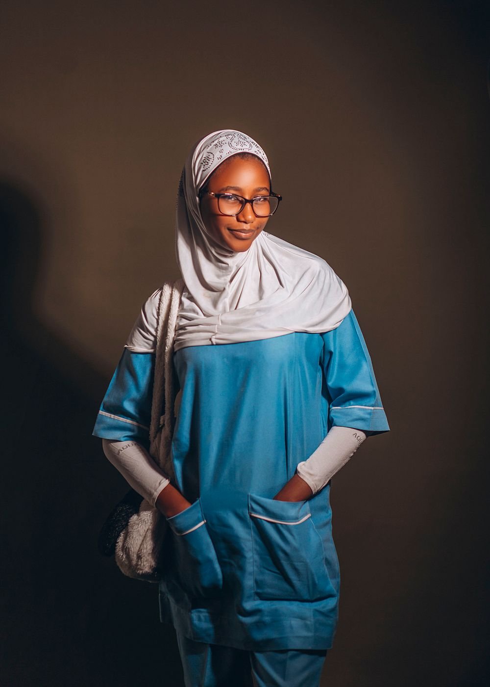 A clinician wearing teal Aichano scrubs and a pale hijab